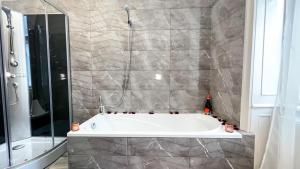 a bathroom with a tub and a glass shower at Flamingo Rezidencia Apartman in Eger