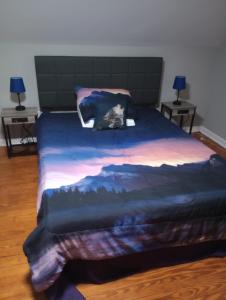 ein Bett mit einer blauen Decke mit einem Bild eines Waldes in der Unterkunft Cozy Suburban Nest in Hopewell