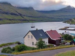 Fjord Guesthouse في Funningsfjørður: منزل على جانب تجمع المياه