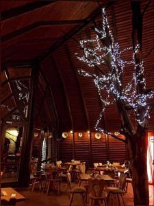 un comedor con mesas y un árbol con luces en Pasa Han Hotel M1autópálya, 