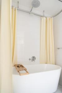 a white bath tub in a bathroom with a shower curtain at Burwood 1bedroom Apartment next to Station in Sydney