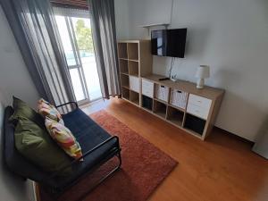 a living room with a chair and a television at Sintra, T3 with terrace in Massama, Queluz, Sintra in Queluz