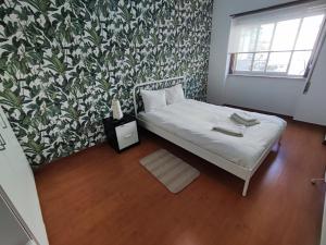 um pequeno quarto com uma cama com papel de parede floral em Sintra, T3 with terrace in Massama, Queluz, Sintra em Queluz