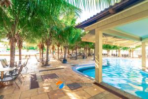 a swimming pool with palm trees and a patio at Apartamentos 2 Quartos- Lacqua diRoma Caldas Novas in Caldas Novas