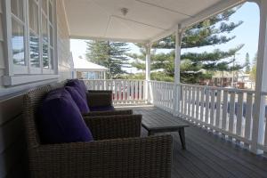 a porch with two wicker chairs and a table at Christina Cottage in South West Rocks