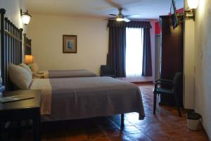 a bedroom with a bed and a desk and a window at Hotel Real de Leyendas in Guanajuato