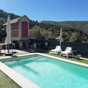 a swimming pool with chairs and a table and umbrellas at Casa do Loureiro - Apartamento in Paradela