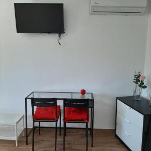 a dining room table with two red chairs and a tv at Casa do Loureiro - Apartamento in Paradela