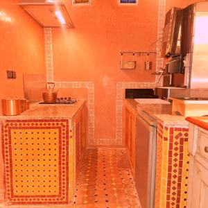 een keuken met oranje muren en een oranje vloer bij Riad Ennaciri in Safi