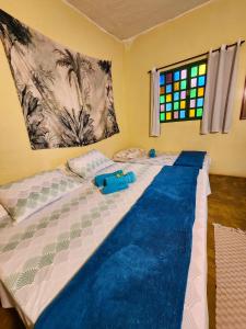 a bedroom with a large bed with a blue blanket at Canto da Coruja - ECOHOSPEDAGEM in Sao Jorge