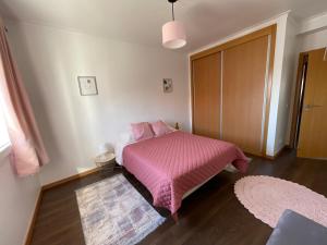 um quarto com uma cama rosa e um cobertor rosa em GARDEN & BEACH HOUSE na Figueira da Foz