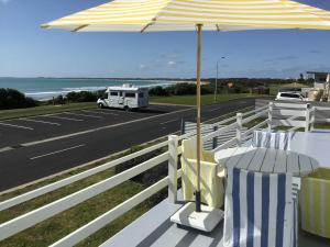 ein gelber und weißer Schirm und Stühle und eine Straße in der Unterkunft Iluka Beach House,Robe- stunning ocean views. in Robe