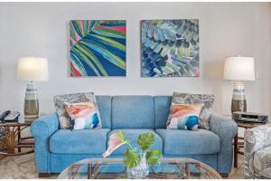 a blue couch in a living room with paintings at KIHEI BEACH, #406^ condo in Kihei