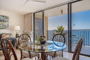 a dining room with a glass table and chairs at KIHEI BEACH, #406^ condo in Kihei +30 photos