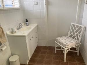 a white bathroom with a sink and a chair at Midgee Cottage in Mudgee