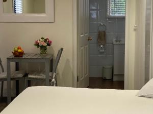 a room with a table with a vase of fruit and a bathroom at Midgee Cottage in Mudgee