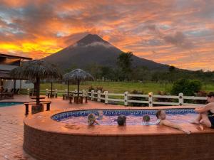 a group of children in a pool with a mountain in the background at Hotel La Pradera del Arenal in Fortuna