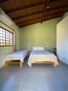 two beds in a room with green walls at Pousada Portal do Cerrado in Pirenópolis