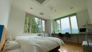 a bedroom with a bed and a desk and windows at Muikamachi Hutte in Minami Uonuma