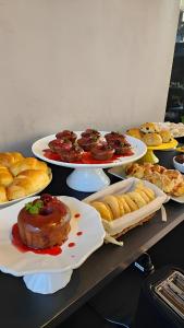 uma mesa com pratos de pastelaria e outros alimentos em Hotel Flores de Holambra em Holambra