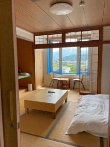 Un dormitorio con una cama y una mesa y una habitación con vistas. en Muikamachi Hutte, en Minami Uonuma