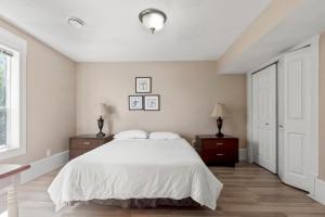 a white bedroom with a bed and two night stands at Executive pet friendly lower suite with ocean view in Ladysmith