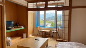 Habitación con cama, TV y ventana. en Muikamachi Hutte, en Minami Uonuma