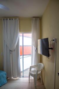 a room with a tv and a chair and a window at Casa do Farol in Itapoa