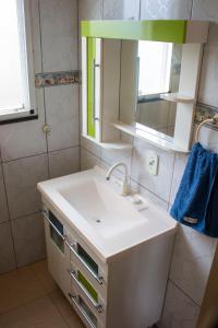 La salle de bains est pourvue d'un lavabo blanc et d'un miroir. dans l'établissement Casa do Farol, à Itapoá