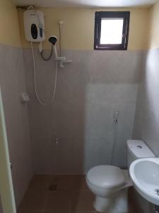 ein Bad mit einem WC, einem Waschbecken und einem Fenster in der Unterkunft Rainbow Pension House in Dipolog City