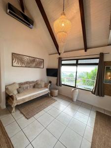 uma sala de estar com um sofá e uma grande janela em BUNGALOW F2 Atypical local style em Faaa
