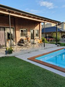 un patio trasero con piscina y una casa en Dormitorio con baño privado, cocina y living compartido con pileta en country en Pergamino