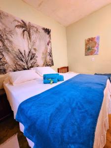 a bedroom with a large bed with a blue blanket on it at Canto da Coruja - ECOHOSPEDAGEM in Sao Jorge