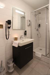 ein Bad mit einem Waschbecken und einer Dusche in der Unterkunft Mille Stelle Hotel in Eggenstein-Leopoldshafen