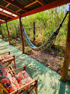 a porch with two chairs and a hammock at Canto da Coruja - ECOHOSPEDAGEM in Sao Jorge