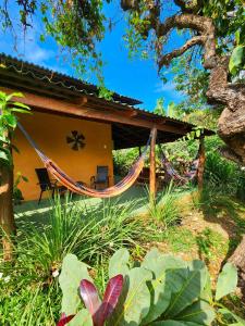 una casa con una hamaca delante en Canto da Coruja - ECOHOSPEDAGEM en Sao Jorge