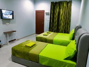 two beds in a room with green sheets at The Marak Village KB - Mini Homestay in Kota Bharu