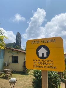 a yellow sign in front of a building with a mountain at Casa Silveira NORONHA in Fernando de Noronha