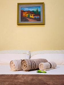 Una cama con toallas y una pintura en la pared. en Canto da Coruja - ECOHOSPEDAGEM en Sao Jorge