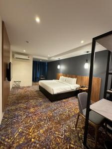 a hotel room with a bed and a table and a chair at Le'genda Hotel in Kajang