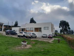 a white house with cars parked in front of it at Casa El Roble paipa in Paipa