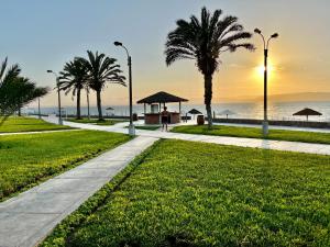 a walkway near the beach with palm trees and the ocean at Suite 1ra Fila Vista Bahía - 100 Metros Las Velas 601 T1 in Paracas