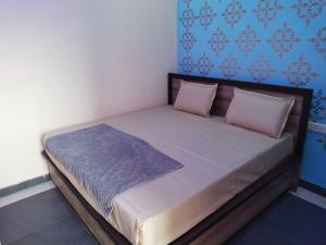 ein Bett mit rosa Kissen und einer blauen Wand in der Unterkunft OYO Blue Dream Palace in Nārnaul