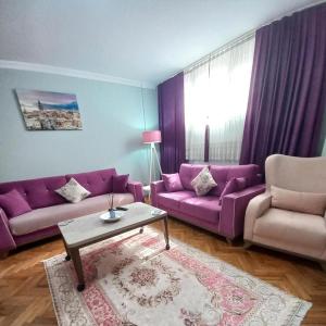 uma sala de estar com sofás roxos e uma mesa em Grand appartement 21 em Istambul