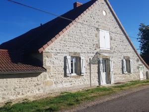 un ancien bâtiment en pierre avec un toit rouge dans l'établissement Gîte Rongères, 2 pièces, 2 personnes - FR-1-489-381, 