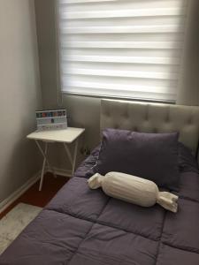 a purple bed with a pillow and a window at Condominio PLaza Club in Temuco