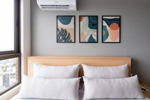 a bedroom with two pillows and three paintings on the wall at Lindo apartamento no melhor do Recife in Recife