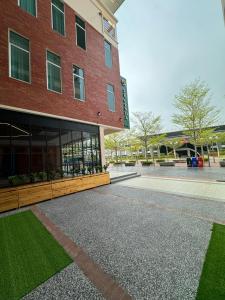 a red brick building with green grass in front of it at Le'genda Hotel in Kajang