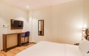 a hotel room with a bed and a desk and a tv at Hotel Deluxe Residency in Mumbai