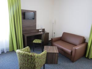 a hotel room with a couch and a desk and a chair at Hotel-Restaurant Zum Stern in Baumholder